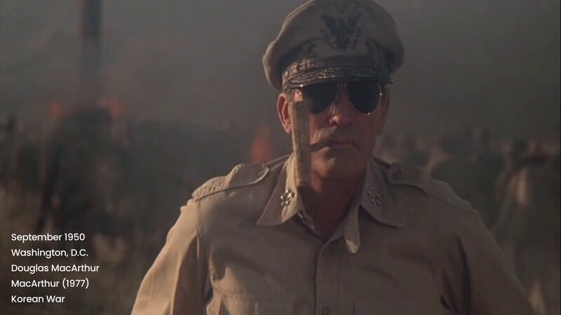 Still from the World War II Supercut, showing a scene from MacArthur (1977). MacArthur is in the foreground, smoking his famous pipe. The background is heavily blurred.
